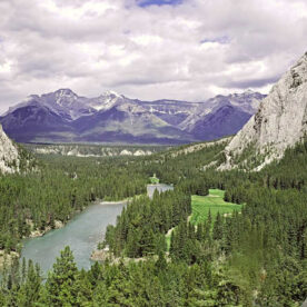 A sweeping view of the Bow Valley with green mountainsides along the Bow River
