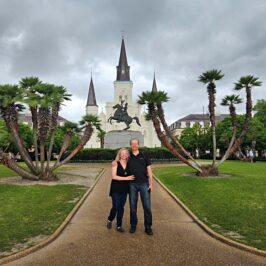 A couple stand in the park in front of a church in New Orleans