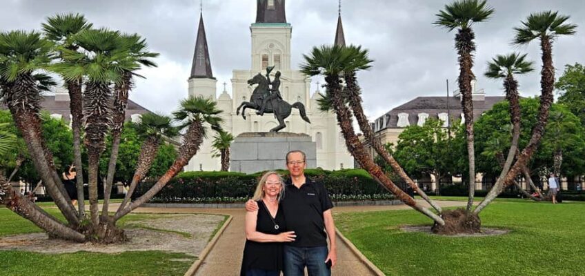A couple stand in the park in front of a church in New Orleans