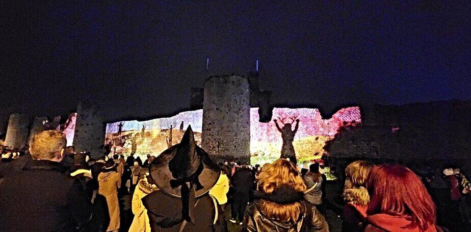 Witches hats and red haired lasses enjoying the illuminations on the walls of Trim Castle at the Puca Festival