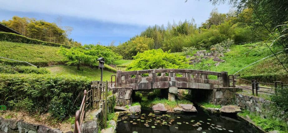 Rakusai Bamboo Park offers quieter walk in a bamboo forest. Image of a stone bridge over a stream with a bamboo forest in the background